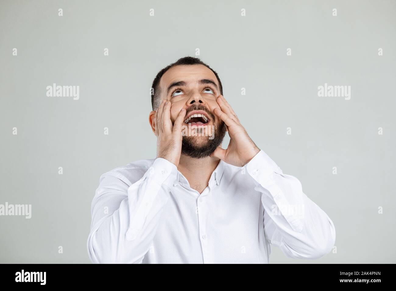 Uomo Barbuto mantiene la mano sulla testa su sfondo grigio. l uomo dimentica qualcosa Foto Stock