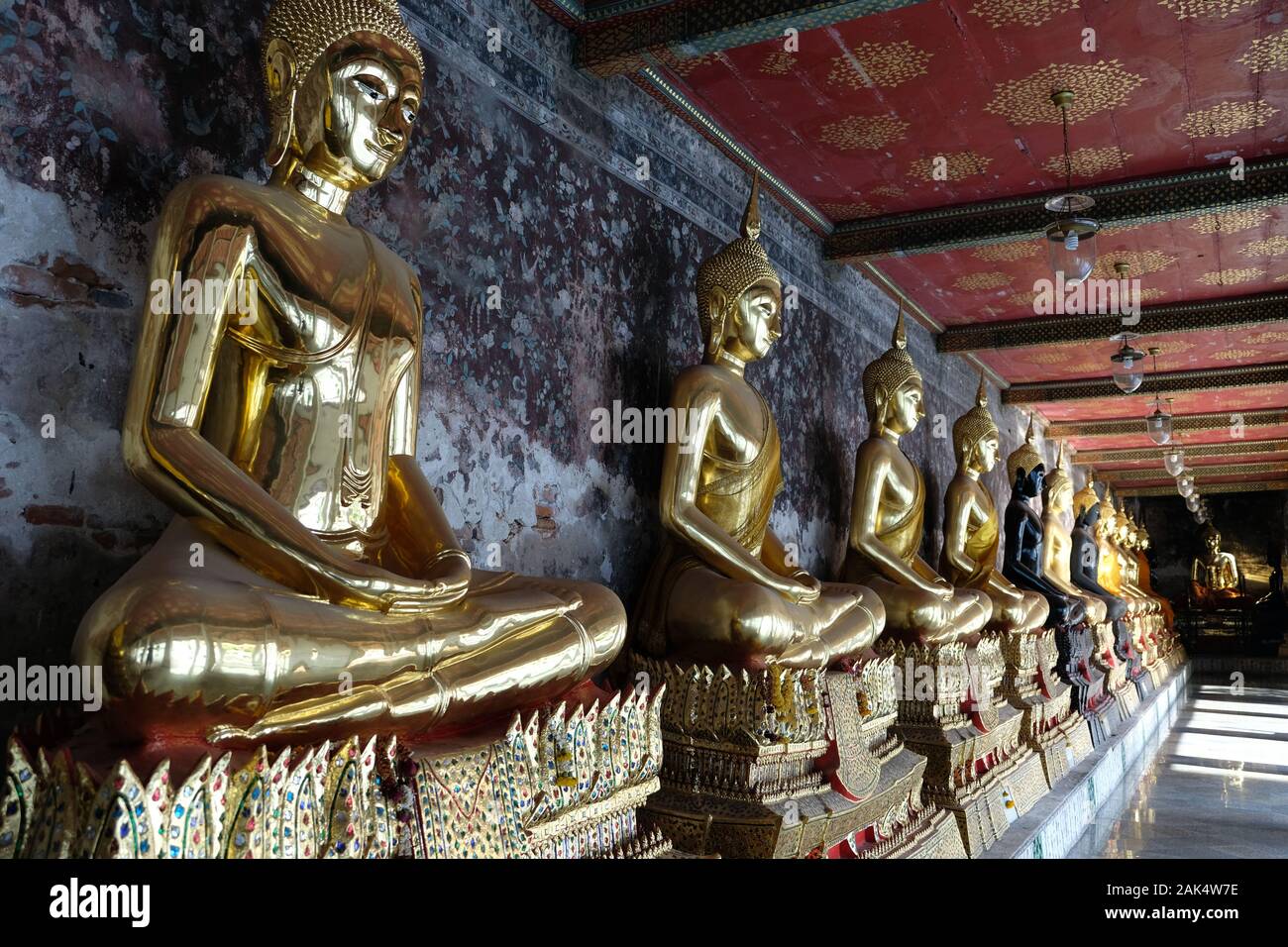 Bangkok Thailandia Wat Suthat Thepwararam tempio - meditando Golden Statue di Buddha seduto in una fila in un corridoio Foto Stock
