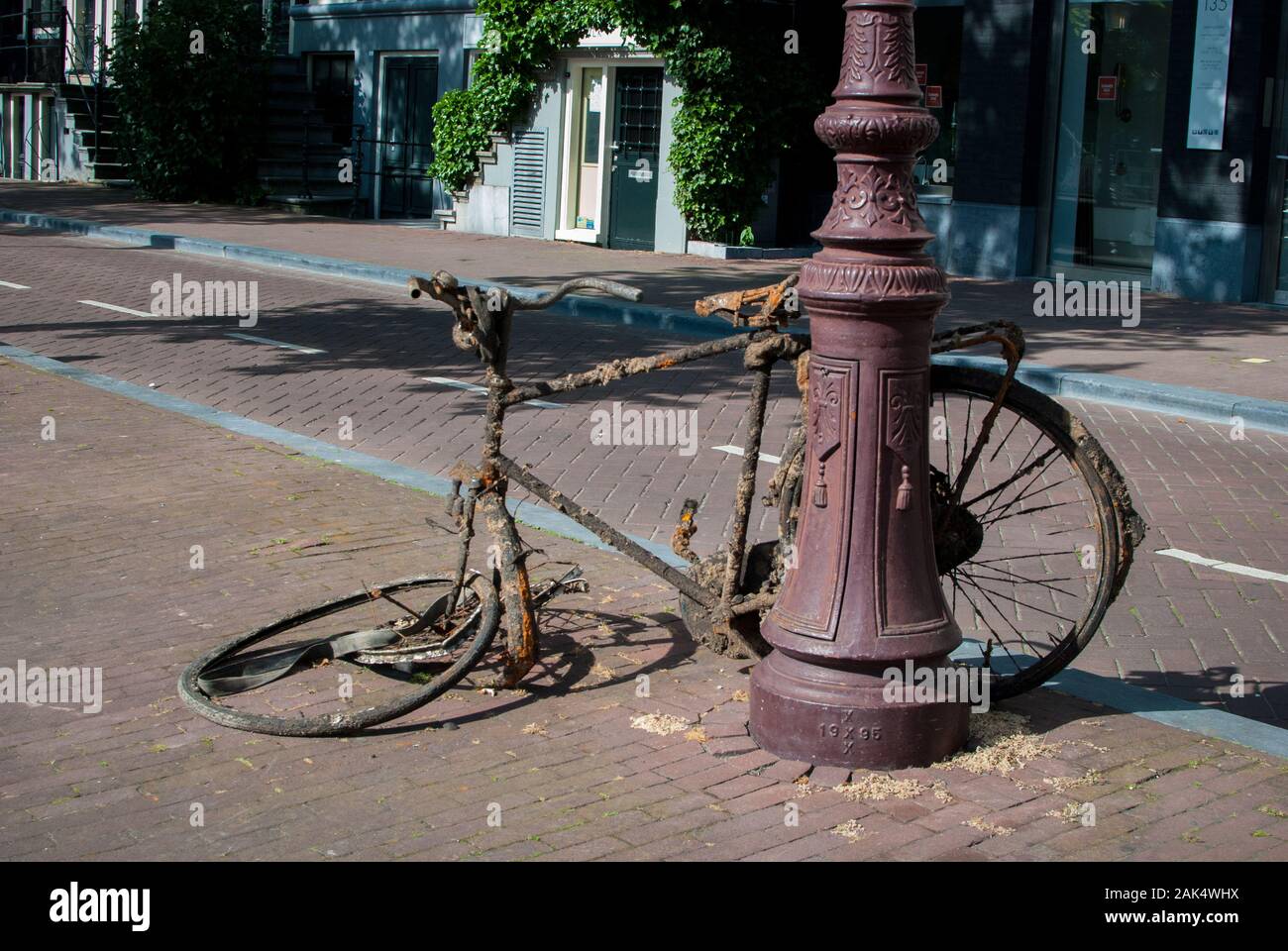 Vecchia bici che ottiene arrugginita parcheggiata nel mezzo della strada Foto Stock