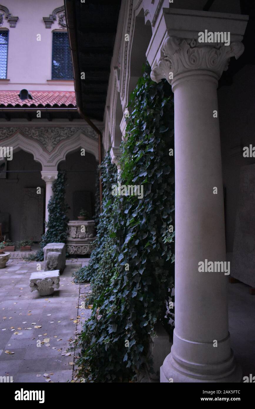 Un edificio che si trova nel giardino di una cattedrale, un tetto rosso, alcune sedie e decorativo piante naturali Foto Stock