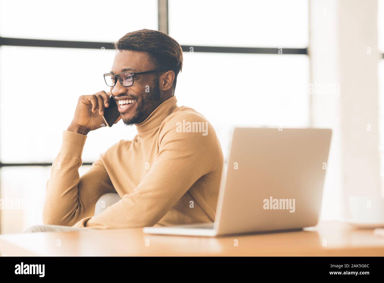 Chiamando la famiglia. Felice studente africano rendendo telefonata ai suoi parenti o ragazza. Spazio libero Foto Stock