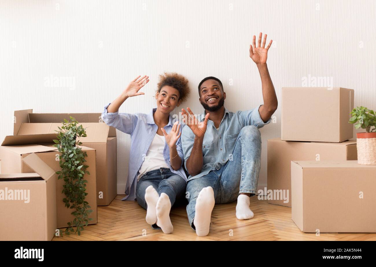 Nuova casa. Afro coniugi a discutere di Interior Design seduta sul pavimento tra le scatole in movimento in casa propria Foto Stock