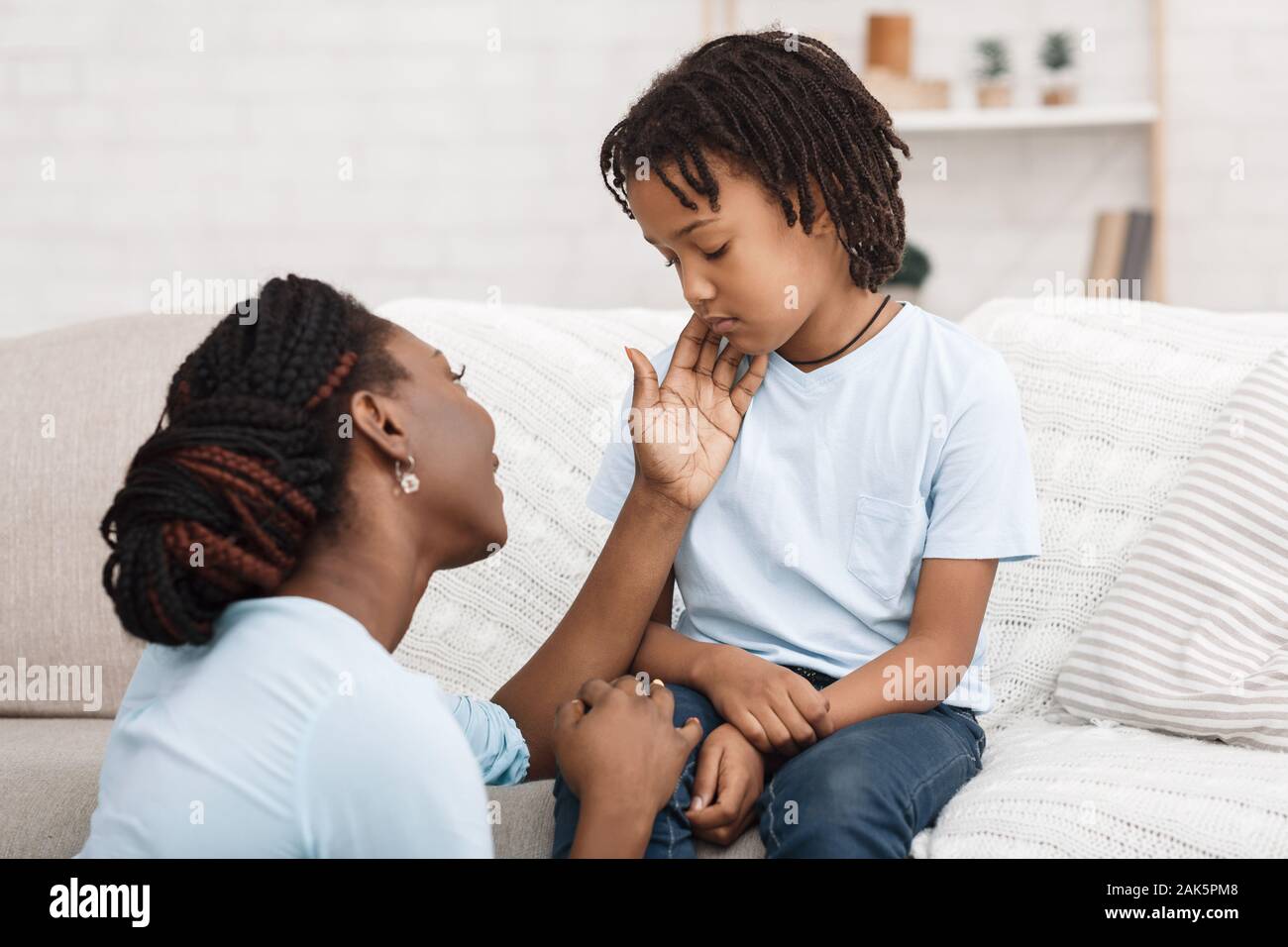 Consolante e cura. Afro madre il supporto di sua figlia sconvolto, scusandosi, accarezzando offeso bambino Foto Stock