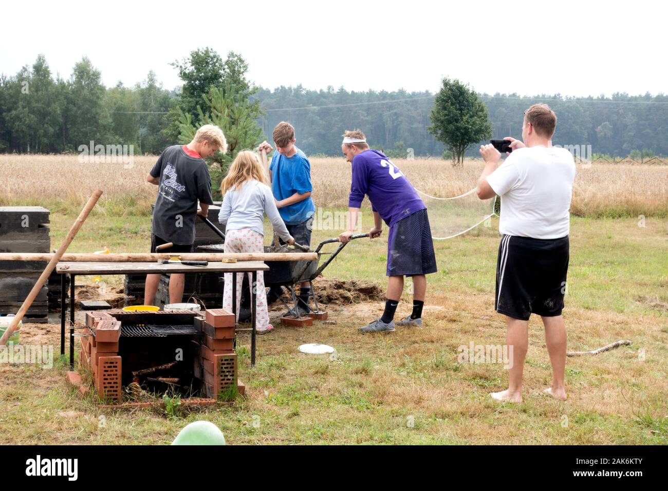 Lo zio di fotografare i cugini la miscelazione di cemento per la costruzione di una famiglia all'aperto camino. Zawady Gmina Polonia Rzeczyca Foto Stock