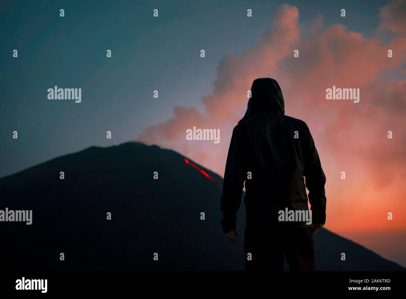 Bel tramonto acceso il fumo e la silhouette di un uomo da dietro guardando il flusso lavico all'attivo vulcano Pacaya, Antigua, Guatemala Foto Stock