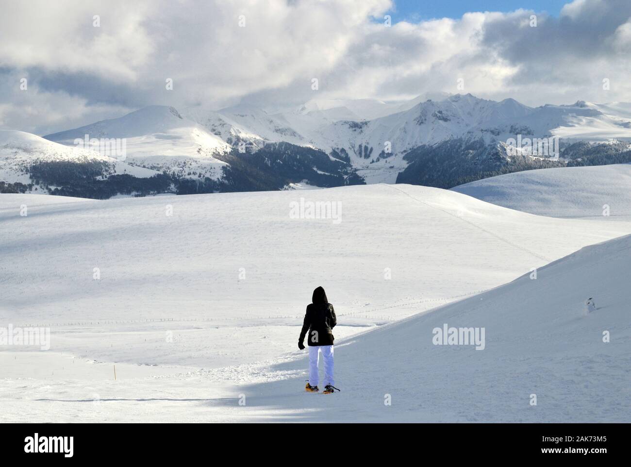 Un escursionista con racchette da neve passeggiate sulla neve, sulla sommità di un nevoso montagna vulcanica Foto Stock
