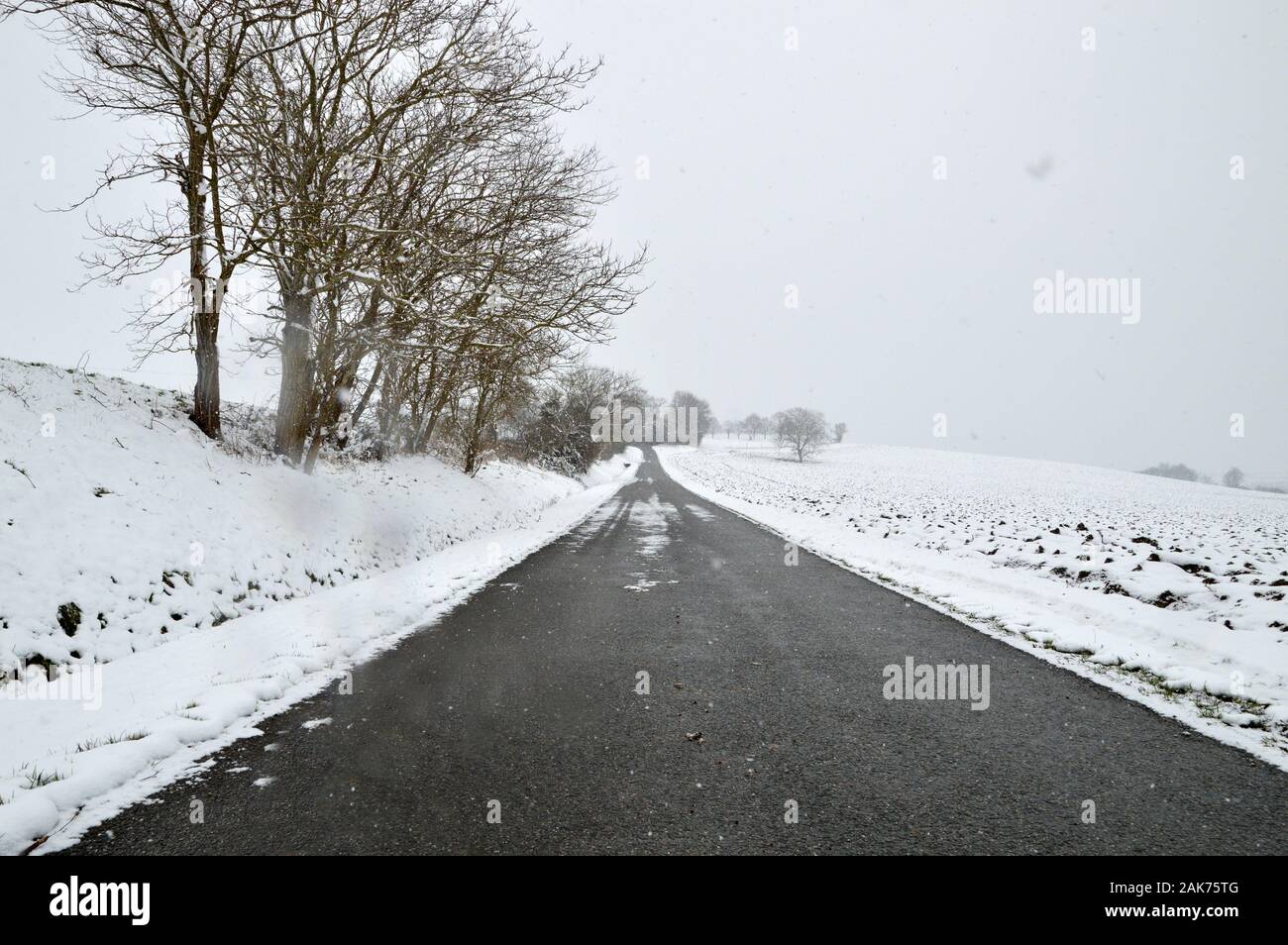 Un pericoloso snowy e scivolose country road durante l inverno con bassa visibilità. Foto Stock