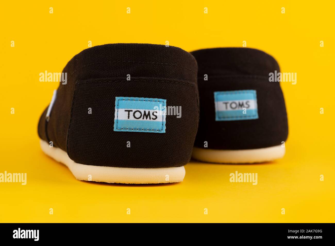 Una coppia di Toms Shoes dall'azienda Collezione Venezia shot su sfondo giallo. Foto Stock