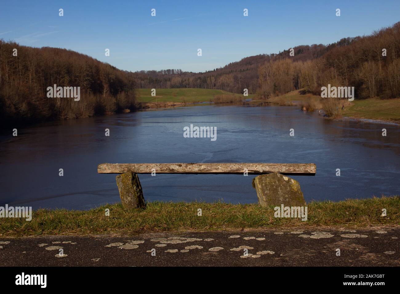 Vuoto inclinato vecchia panca su una collina che si affaccia su un lago ghiacciato Foto Stock