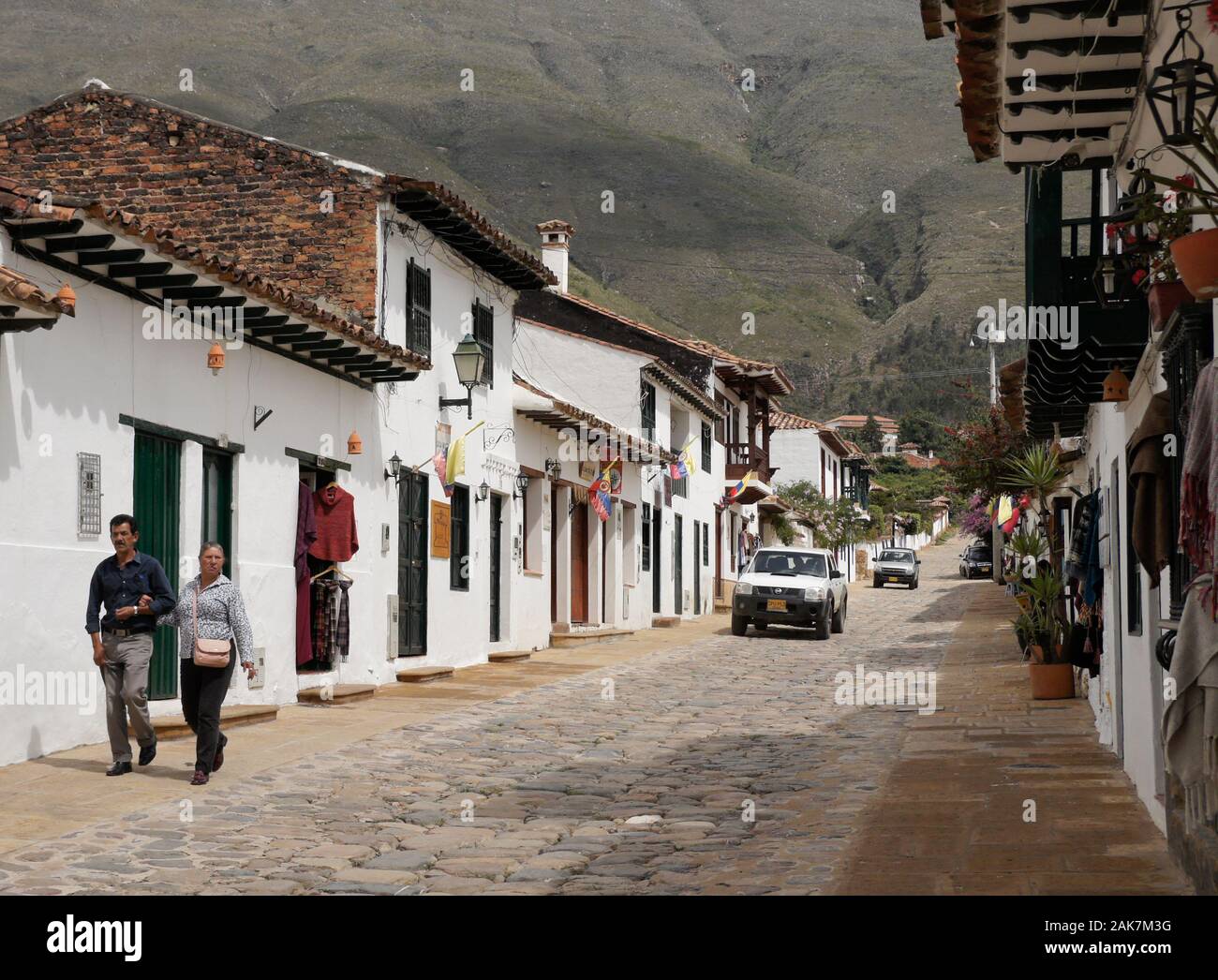 La terracotta con soffitto dipinto di bianco, gli edifici coloniali su una strada acciottolata costeggiata da negozi, Villa de Leyva, Colombia Foto Stock