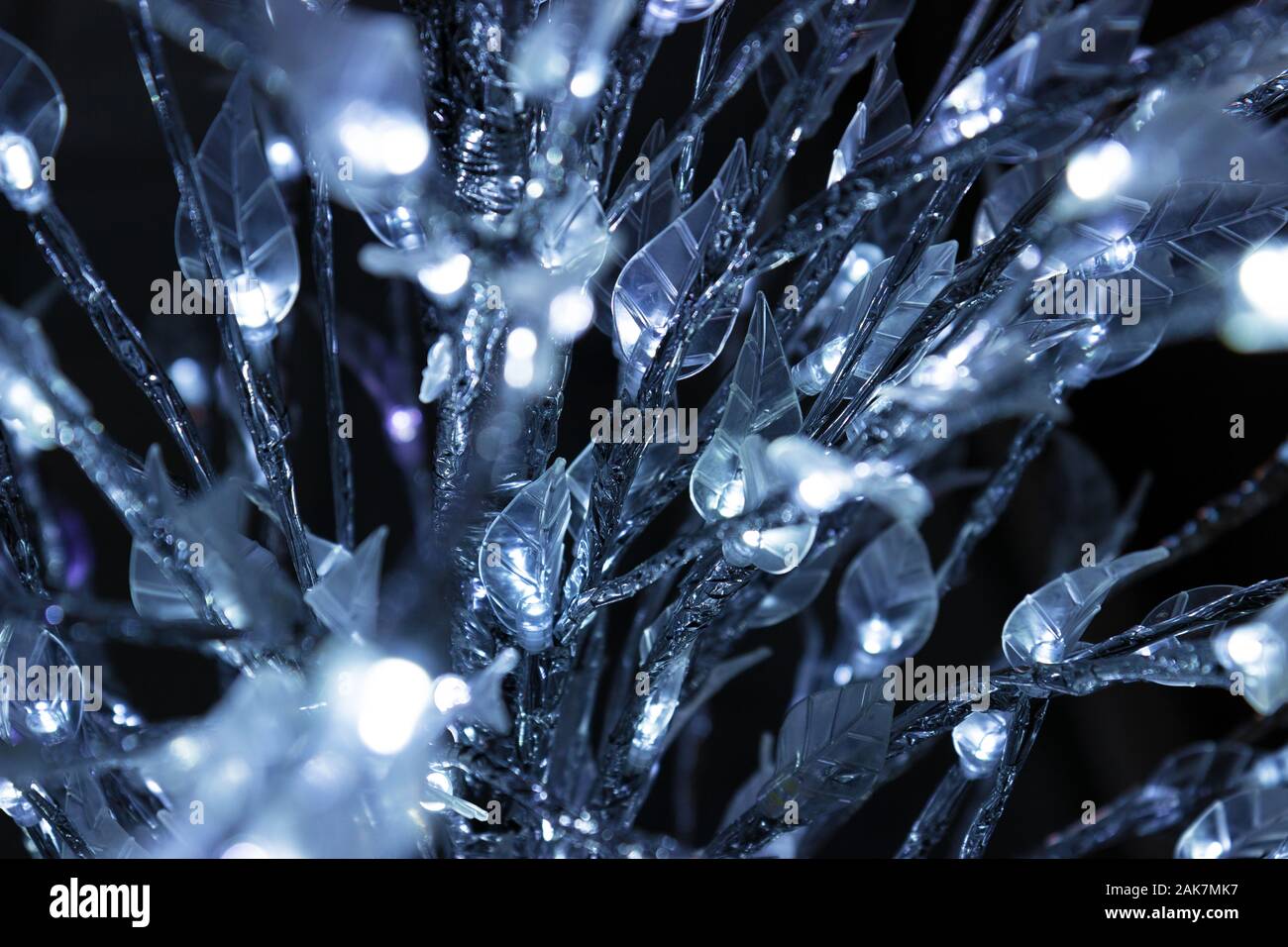 Prima vista di un albero artificiale con luci LED bianche fredde e foglie trasparenti, sfondo di decorazione natalizia luminosa Foto Stock