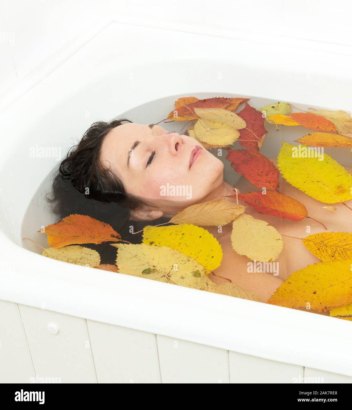 Donna di balneazione con foglie di autunno Foto Stock
