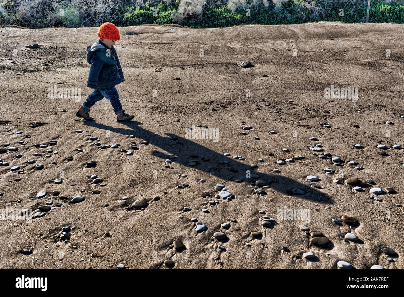 Tre anni baby boy camminando su una spiaggia deserta in inverno Foto Stock