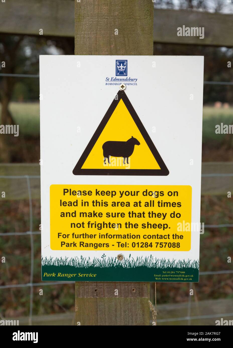 Un segno che richiede i cani è tenuto su un cavo sempre nella zona pecore stanno pascolando Foto Stock