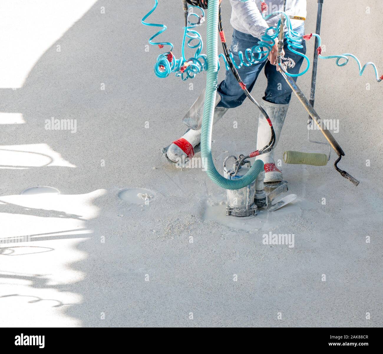 Uomo con un cannello al propano, rullo, e la coppa pompa durante una piscina ristrutturazione Foto Stock