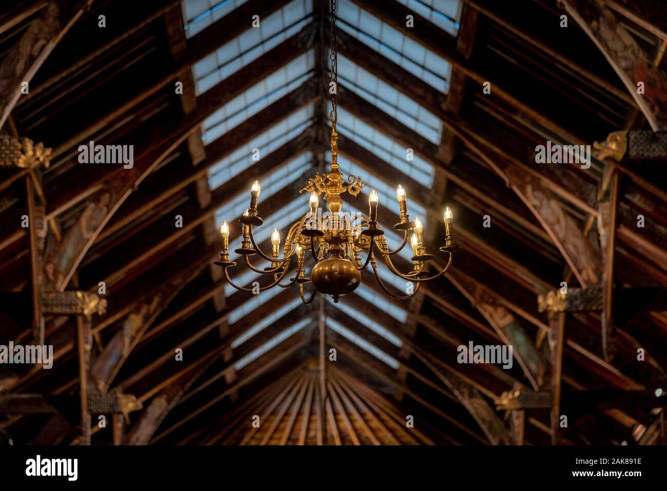 Bella illuminata golden lampadario appeso sotto massimale sfocate, pieno di dettagli con la statuetta di trombe. Foto Stock