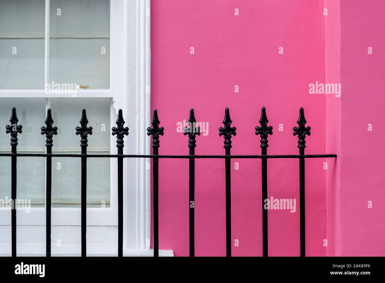 Rosa colorata casa a schiera, finestra e ringhiere in ferro battuto astratta. Chelsea, Royal Borough di Kensington e Chelsea, Londra, Inghilterra Foto Stock