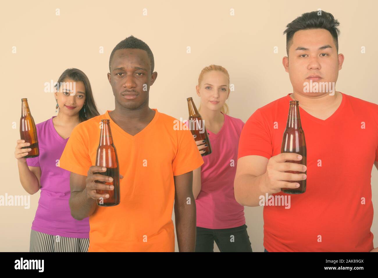 Studio shot del variegato gruppo di multi etnico azienda amici bottiglia di birra insieme Foto Stock