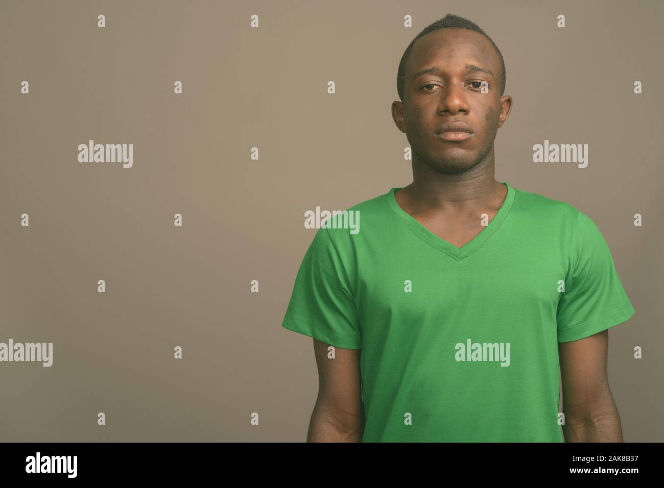 Giovane africano indossando camicia verde contro lo sfondo grigio Foto Stock