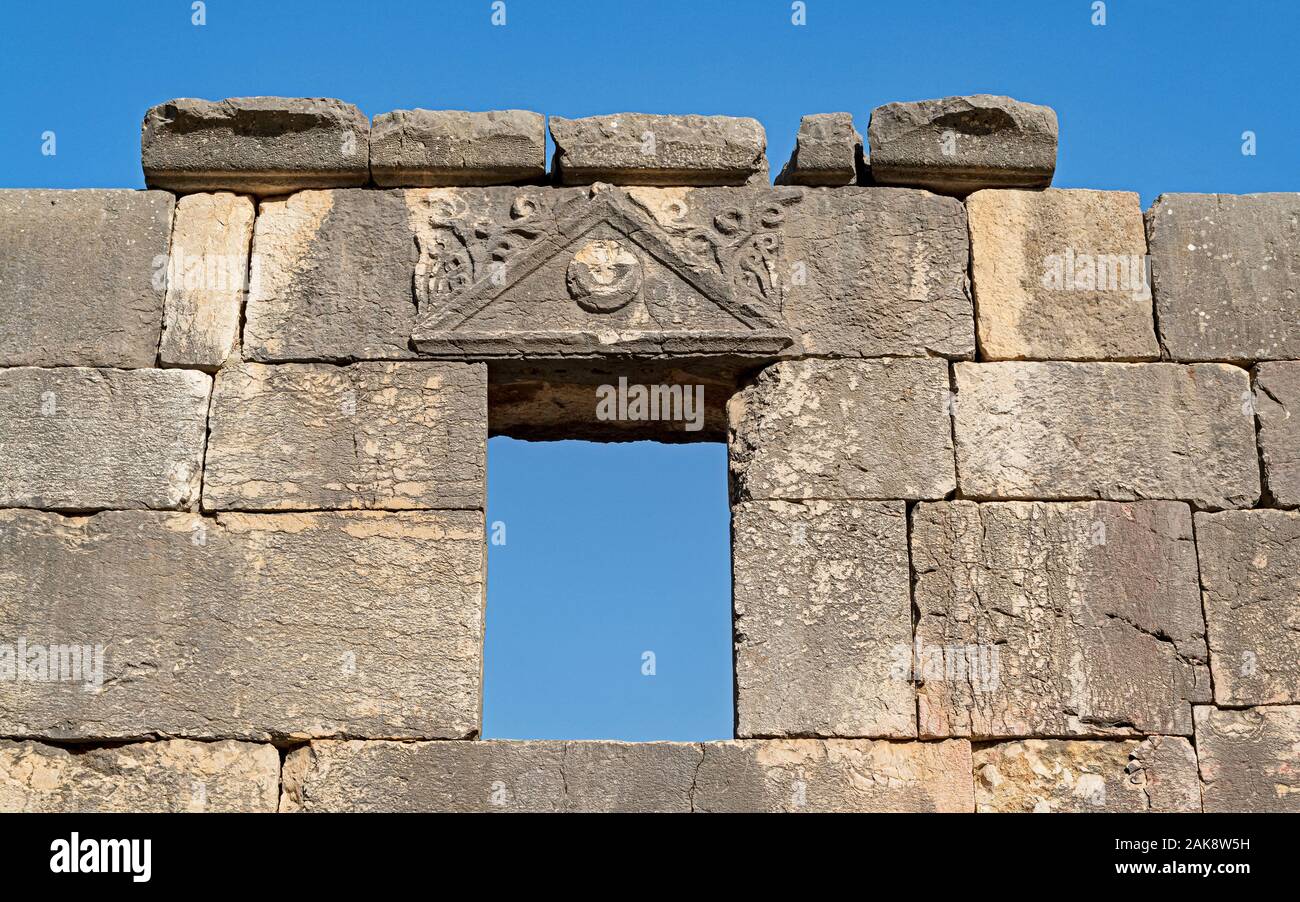 In pietra basaltica finestra e splendidamente scolpito sull'architrave del l'antica sinagoga di baraam parco nazionale in Israele su un cielo sfondo blu Foto Stock