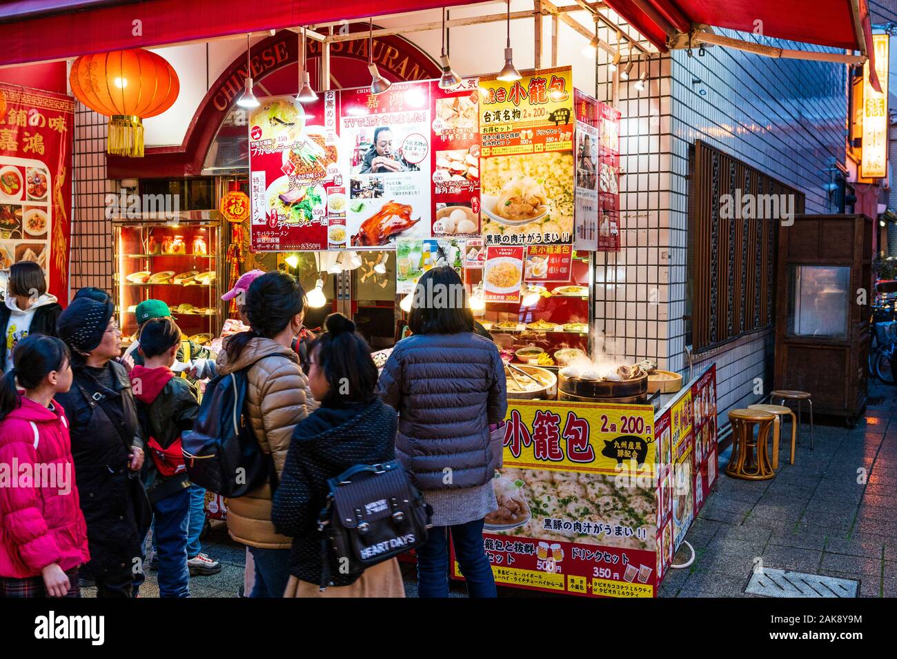 Chinatown, Nankin-Machi in Motomachi, Kobe, Giappone. Persone che acquistano cinese il cibo di strada da piccole bancarella vendendo tagliatelle, gnocchi e Gyoza. Di sera. Foto Stock