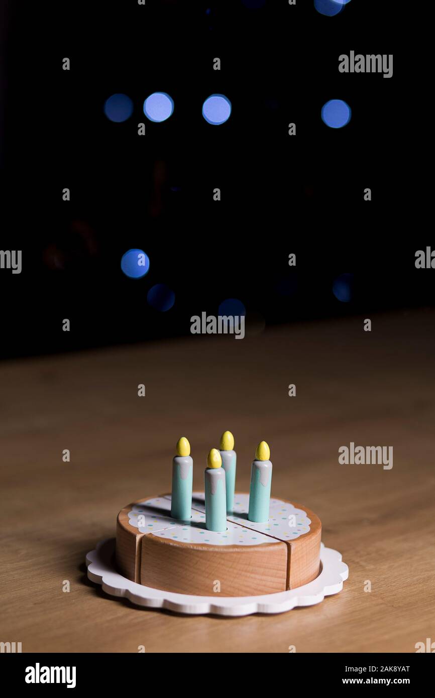 Toy festa di compleanno torta isolato su una superficie in legno su uno sfondo scuro con faretti Foto Stock