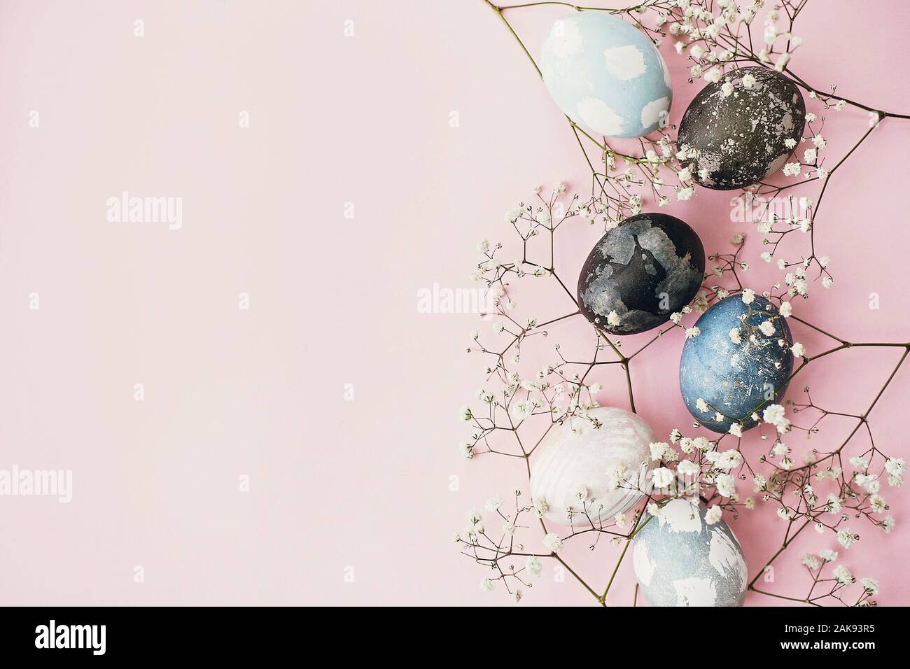 Felice Pasqua composizione. Elegante uova di pasqua e fiori di primavera bordo su carta rosa laici piana, spazio per il testo. Naturale moderno tinti di blu e marmo ea Foto Stock