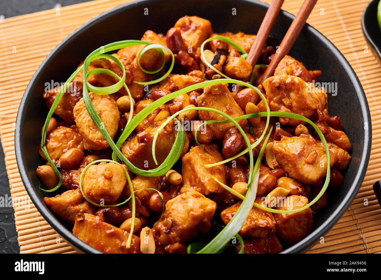 Kung Pao o pollo Gong Bao Ji Ding in ardesia scuro dello sfondo. Sichuan Kung Pao è la cucina cinese è piatto con carne di pollo, peperoncino, arachidi, sa Foto Stock