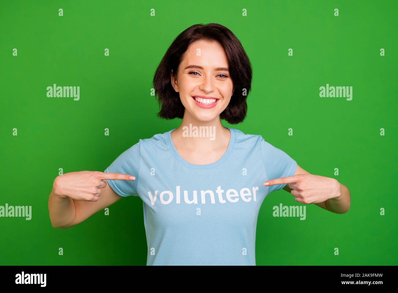 Close-up ritratto di lei bella attraente bella Allegro vivace ragazza che indossa blu t-shirt puntando alla stessa organizzazione di volontariato isolate su Foto Stock