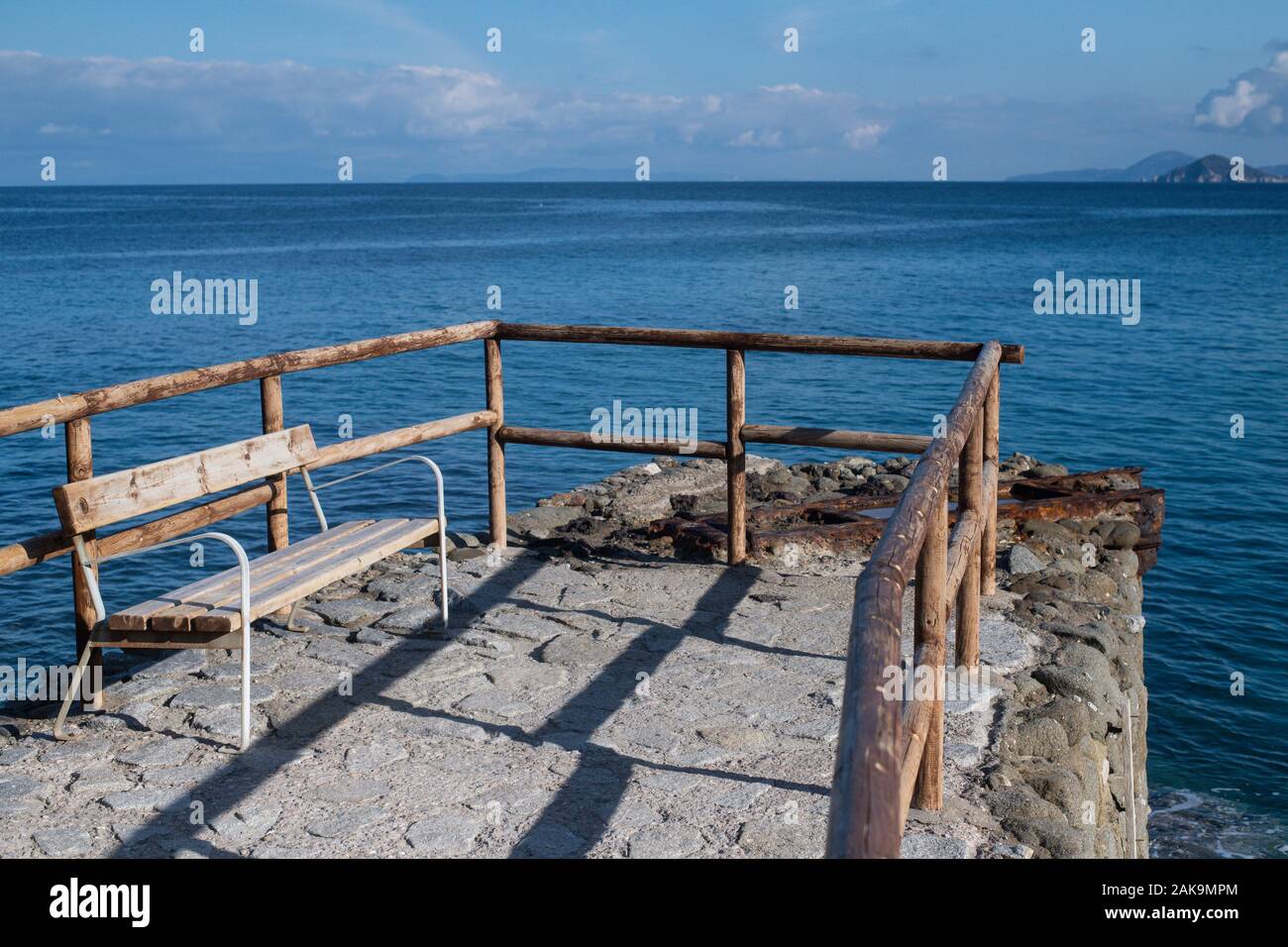 Svuotare panca in legno e ringhiera di fronte al mar Mediterraneo a Sant'Andrea, Isola d'Elba e Arcipelago Toscano, Italia Foto Stock