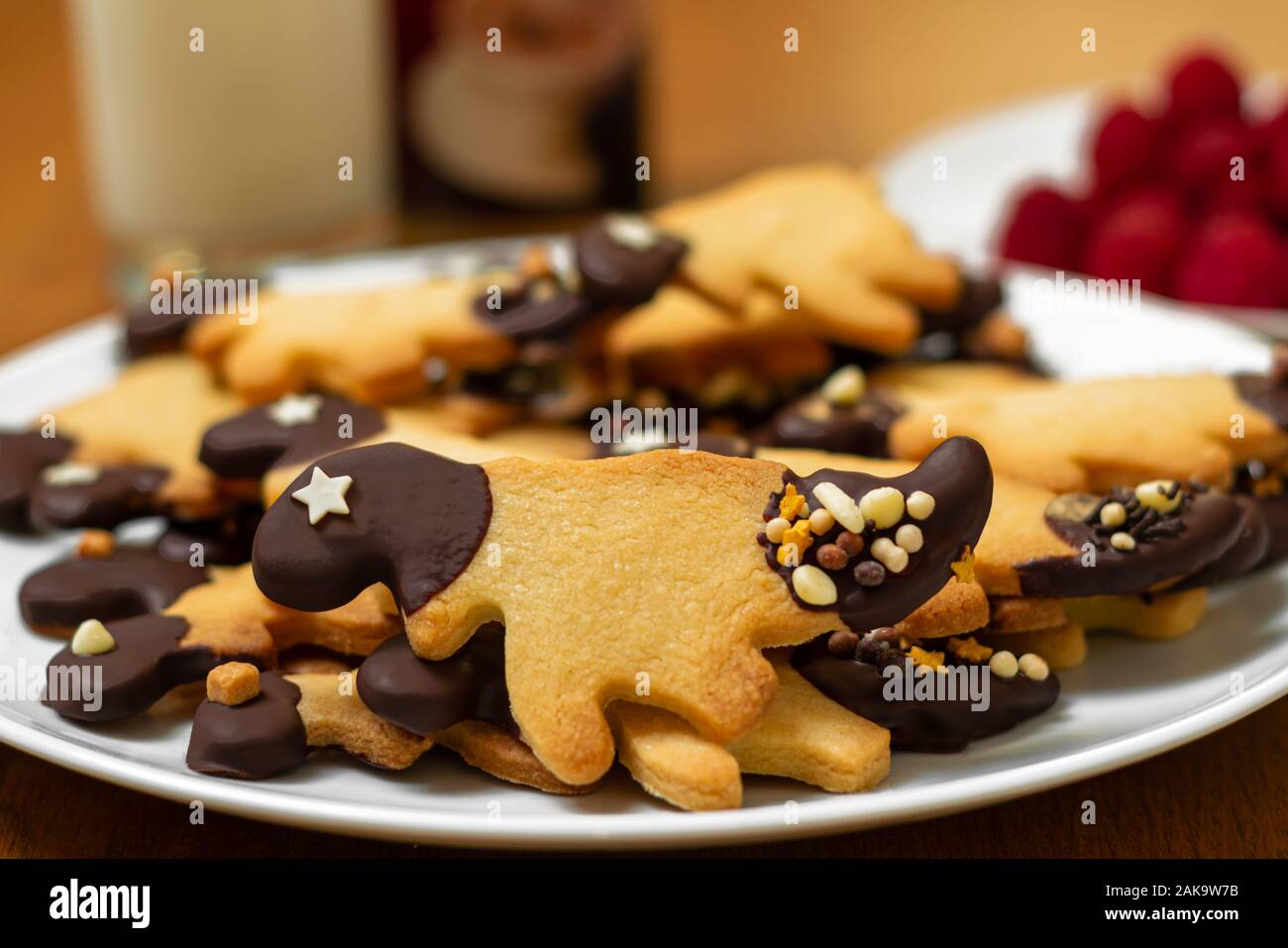 Una piastra di forma di dinosauro, cioccolato e cospargete il tutto immerso i cookie con i lamponi e il latte in una tabella Foto Stock