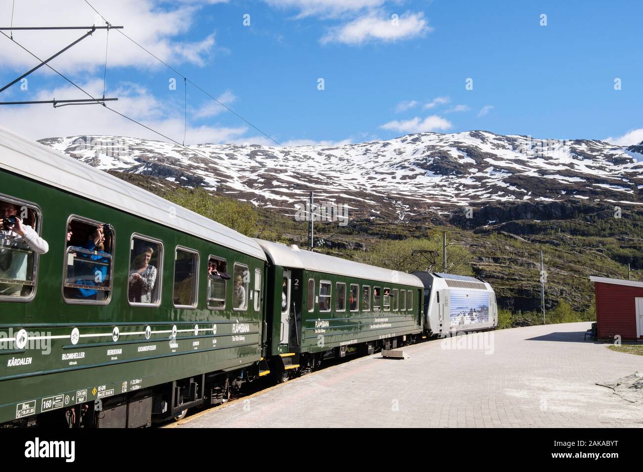 Viaggi turistici su Flam convoglio ferroviario dalla piattaforma della stazione con vista panoramica sulle montagne incappucciate di neve. Vatnahelsen, Aurland, Norvegia e Scandinavia Foto Stock