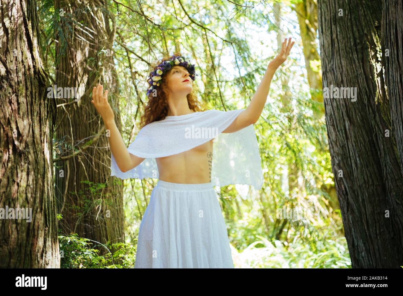 Donna con la corona di fiori in posa nella foresta, Bainbridge Island, nello Stato di Washington, USA Foto Stock