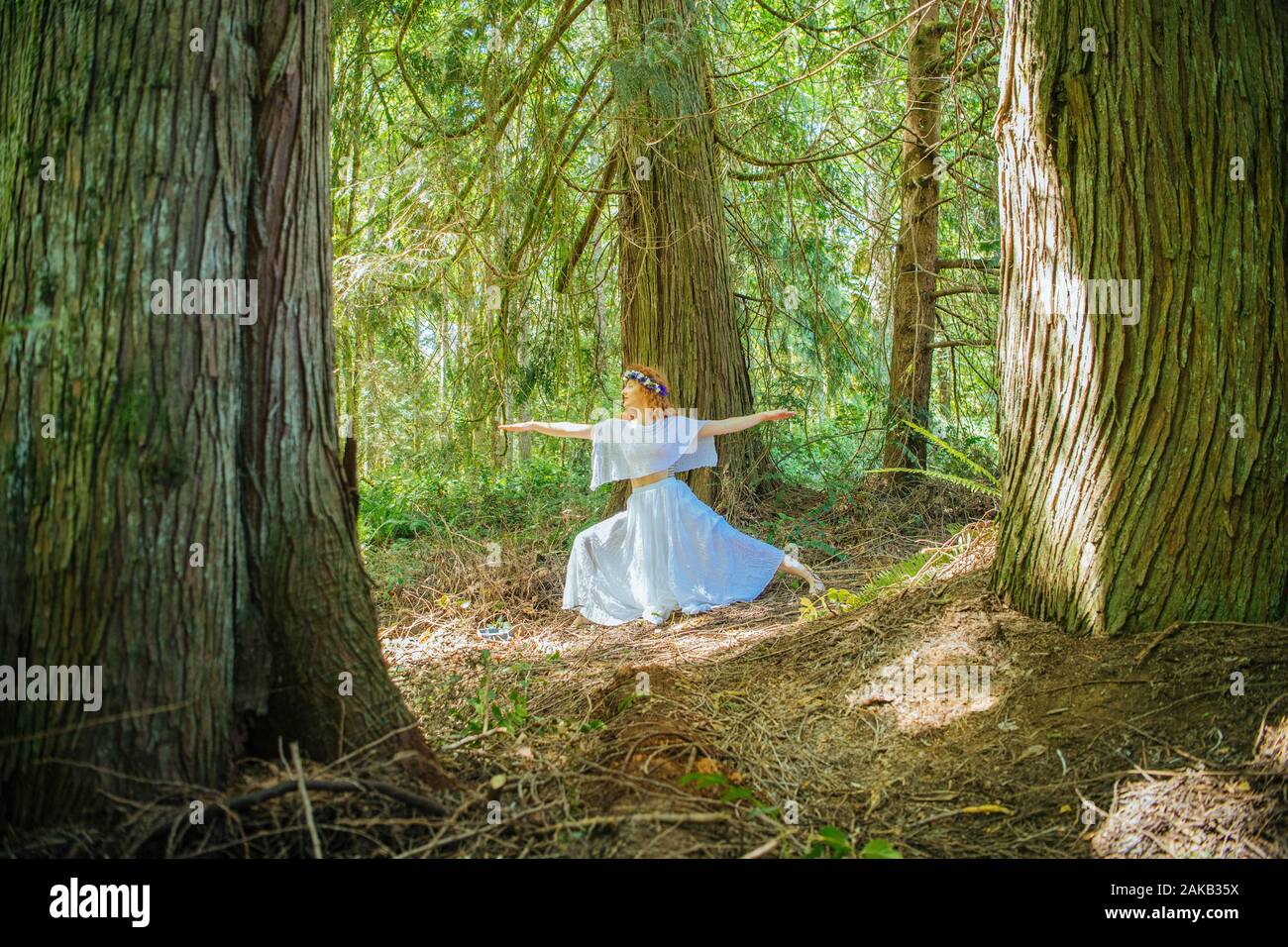 Donna con fiore in posa nella foresta, Bainbridge Island, nello Stato di Washington, USA Foto Stock