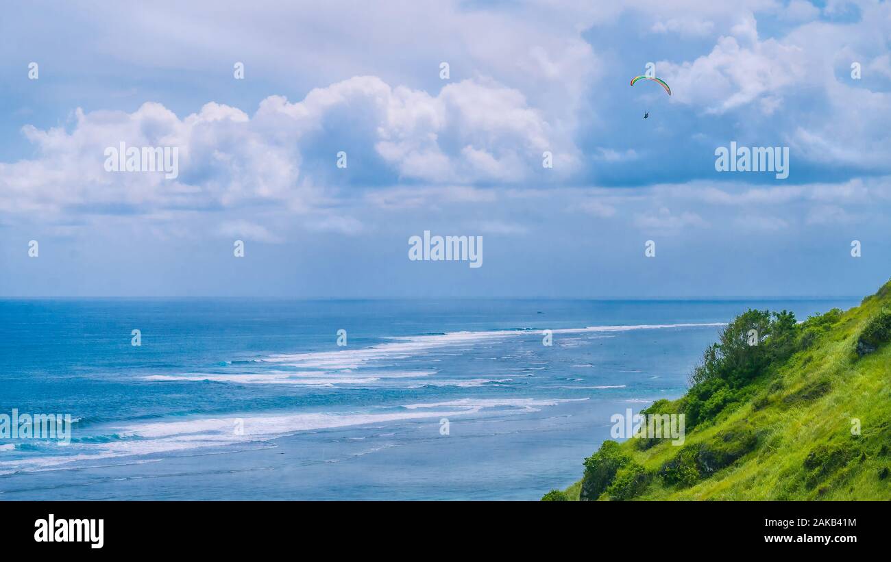 Parapendio volare le colline erbose sopra Gunung Payung spiaggia nella zona nord-est di Bali una delle famose zone per il parapendio Foto Stock