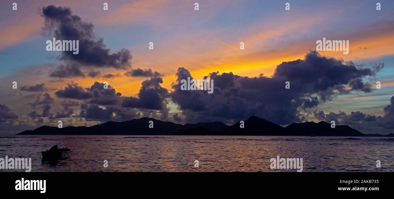 Stagliano barca da pesca in mare al tramonto con l'isola di Praslin in background, La Digue, Seicelle Foto Stock