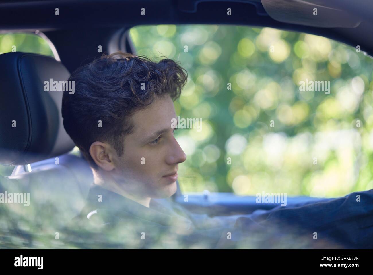 Primo piano di un giovane conducente seduto rilassato in auto Foto Stock