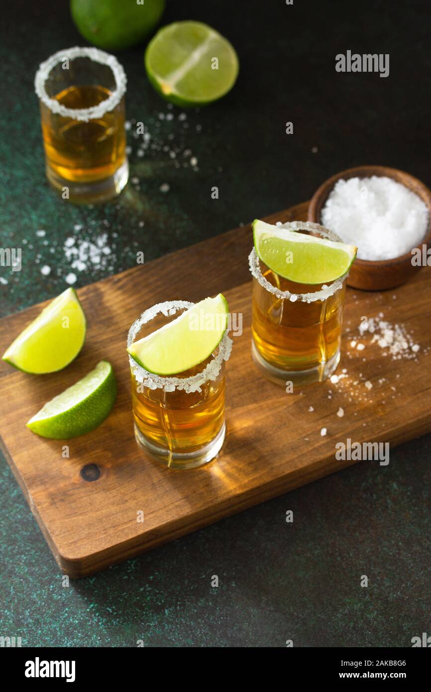 Mexican Gold Tequila shot con calce e sale sulla pietra scuro dello sfondo. Foto Stock