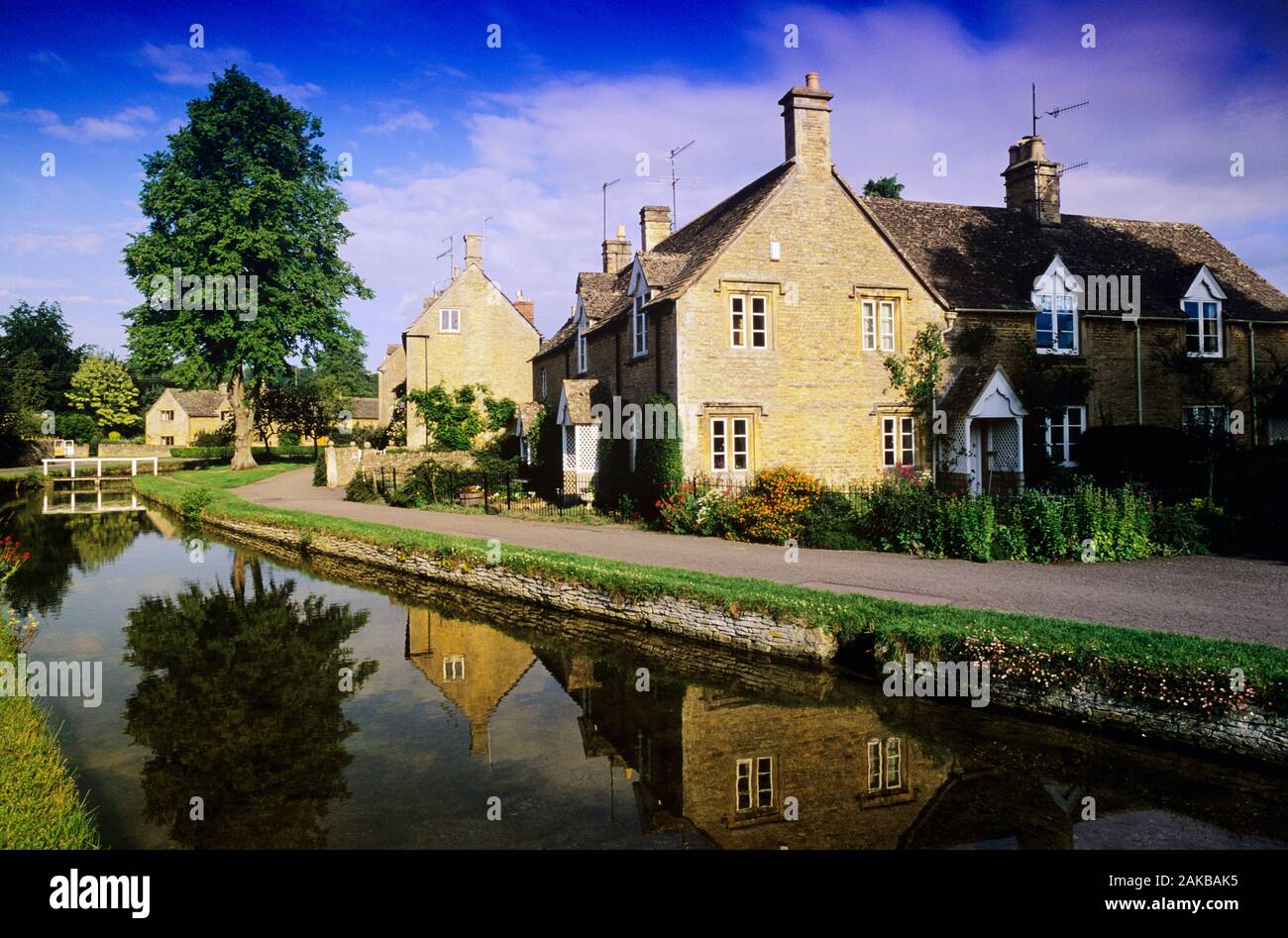 Vista della casa si riflette nel canal, Cotswolds, Gloucestershire, Inghilterra Foto Stock