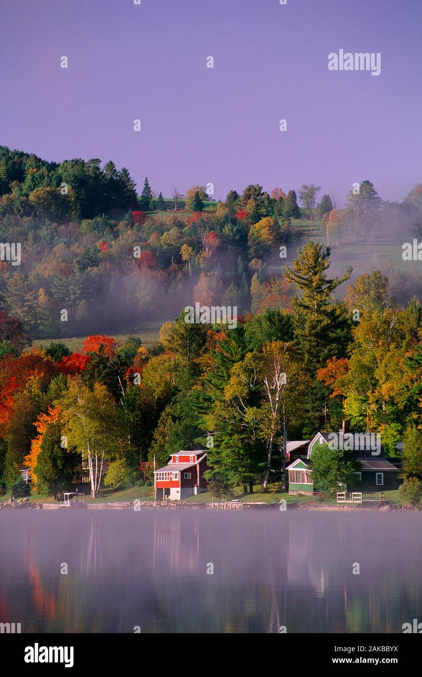 Paesaggio con case e alberi sul lungolago in autunno a sunrise, West Barnet, Vermont, USA Foto Stock