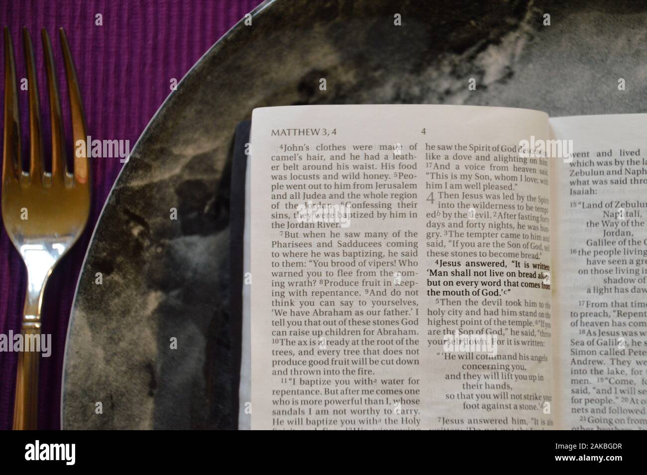 La Bibbia aperta fino a Matteo 4:4 su una piastra di cena su un cartellone viola con argenti in quaresima Foto Stock