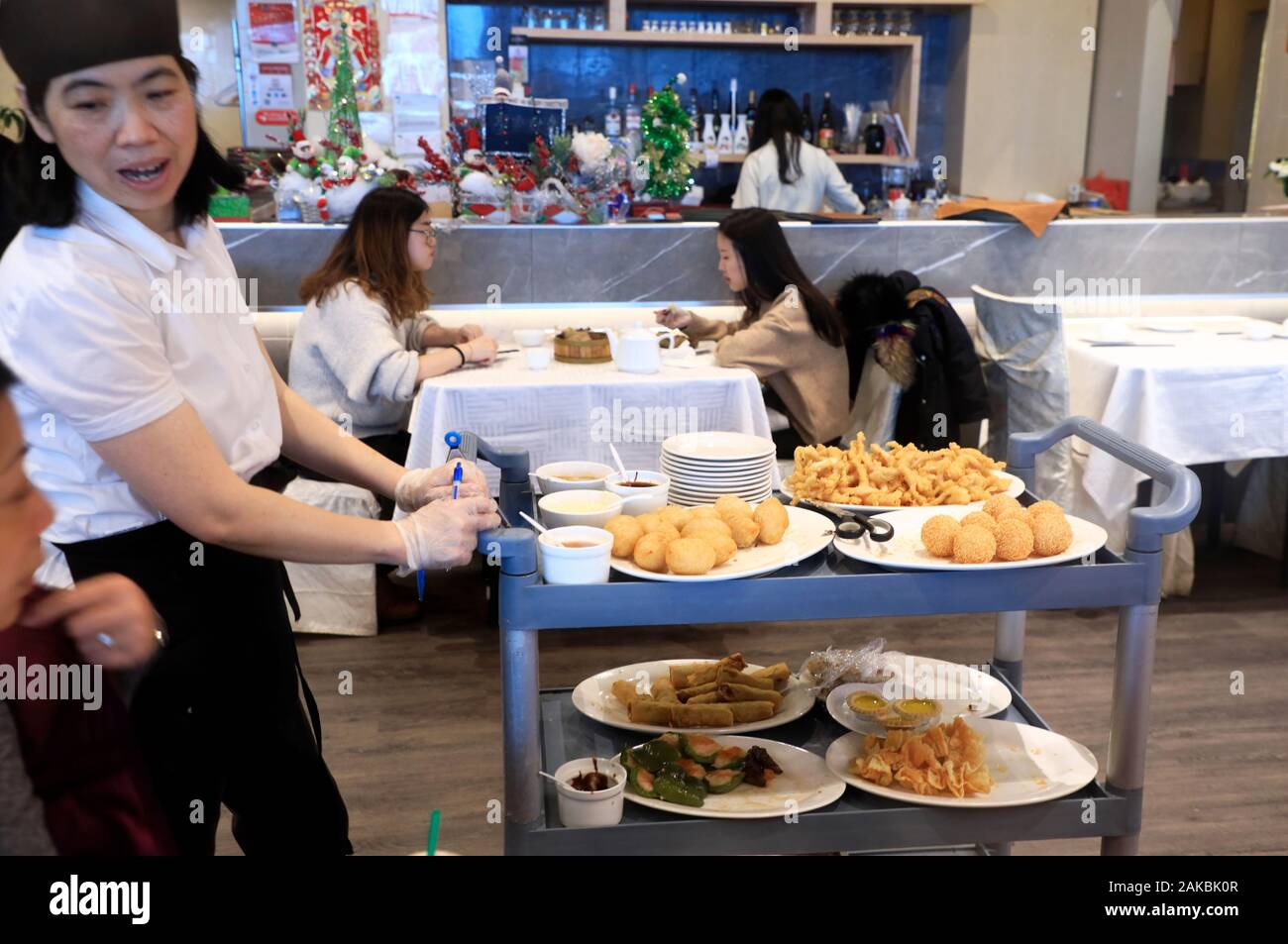 Una cameriera con carrello di spinta che porta piatti dim sum a parlare con il cliente nel ristorante Imperiale un Cantonese dim sum specialista in Chinatown.Montreal.Québec.Canada Foto Stock