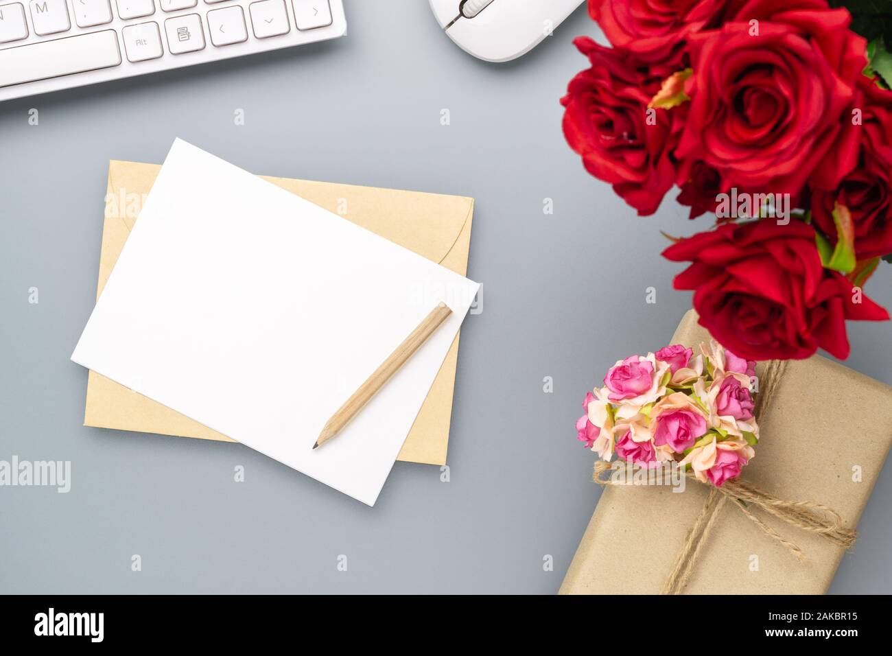 Mockup cartolina vuota e la busta su grigio home office sfondo tabella con rose fiore. Mock up per un design elegante. Flat Top laici vista con copia spac Foto Stock