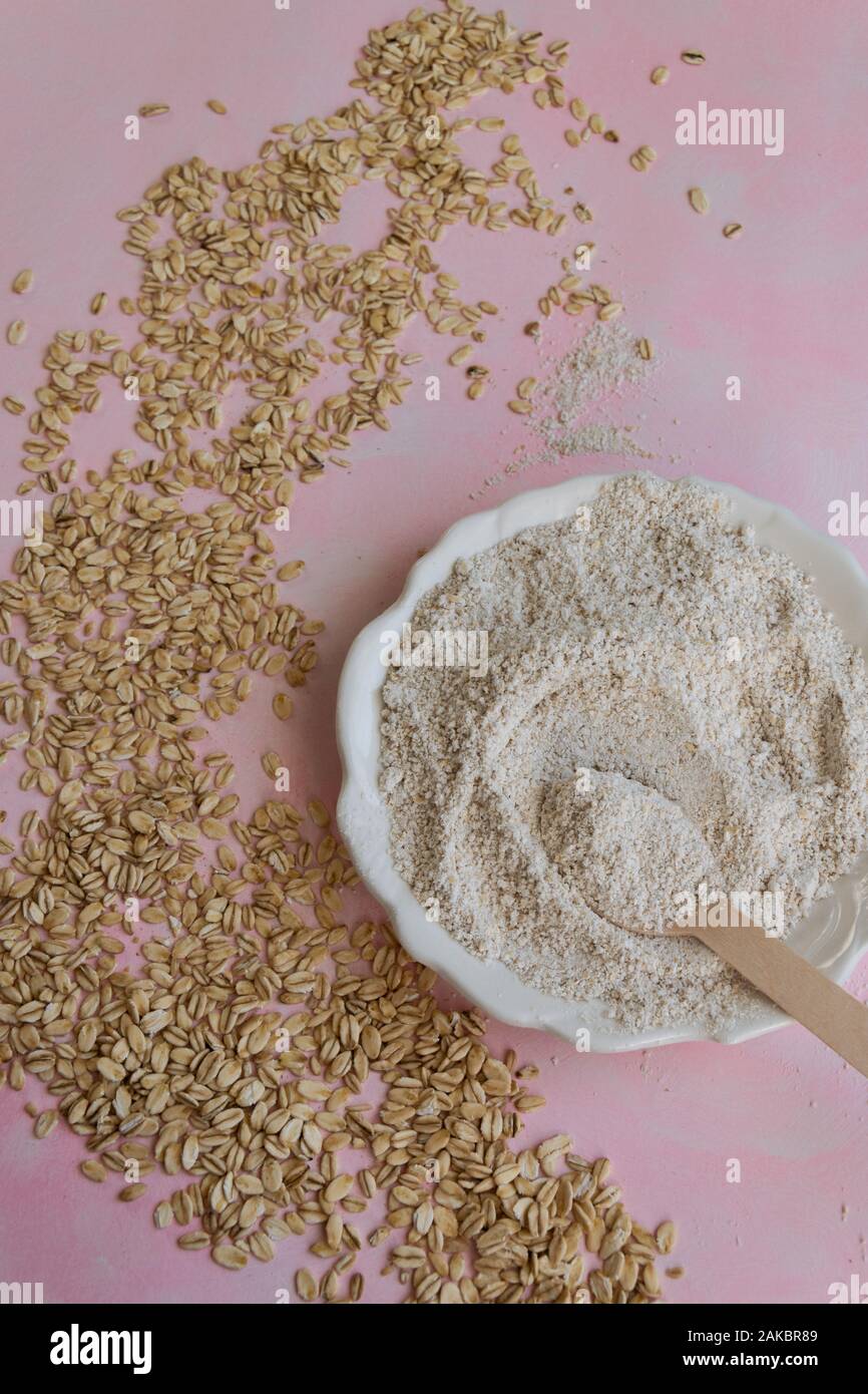 Oat ingredienti alimentari - farine e scaglie su sfondo rosa Foto Stock