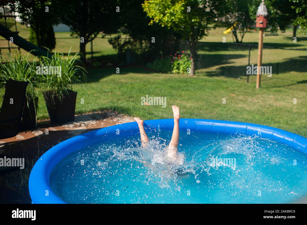 Il ragazzo di 7-8 anni si tuffa nella piscina all'aperto durante la pausa estiva Foto Stock