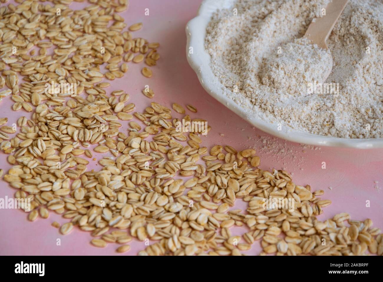 Oat ingredienti alimentari - farine e scaglie su sfondo rosa Foto Stock