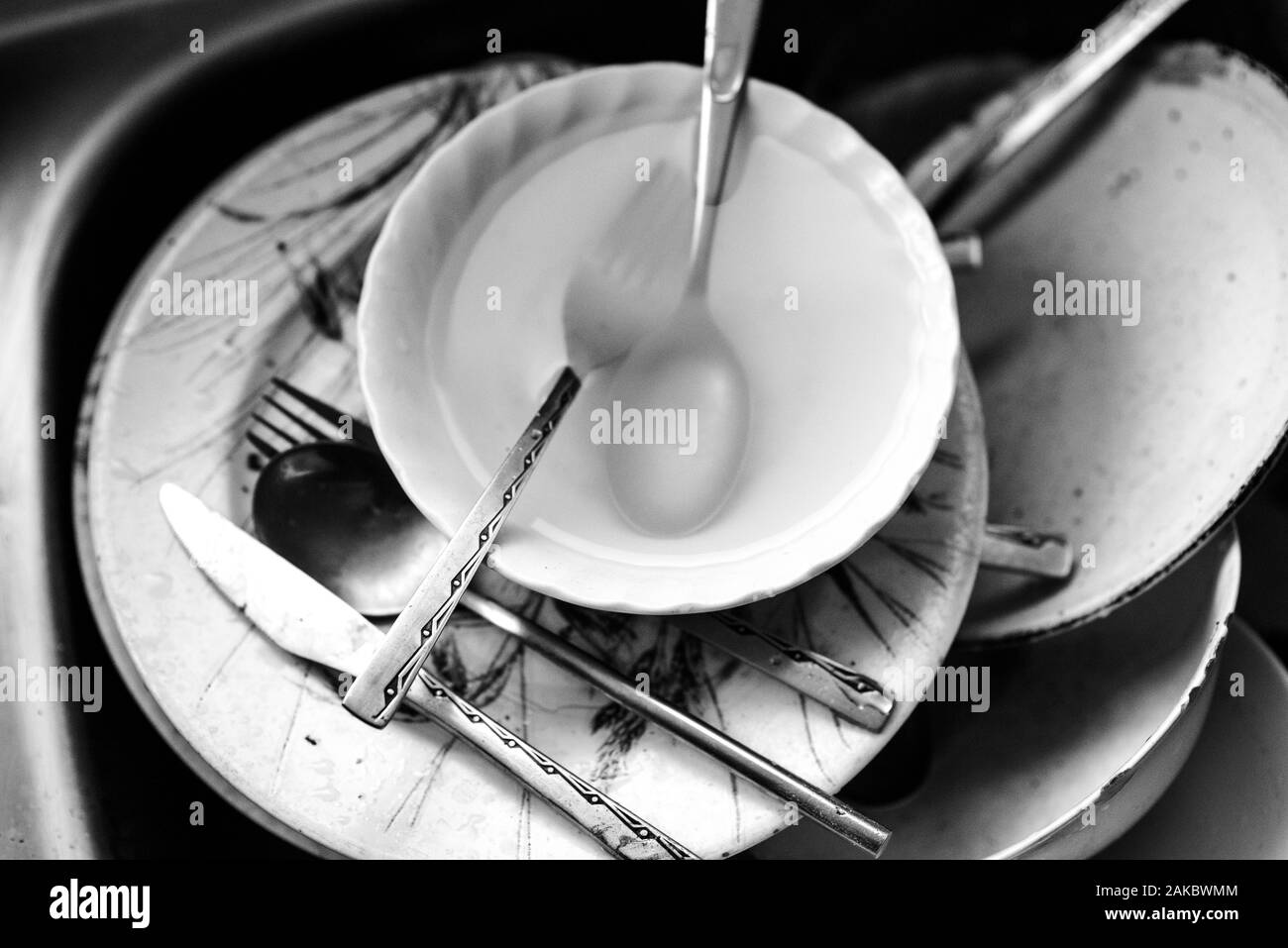Un bianco e nero di sporco piatti, ciotole e posate in lavello da cucina in attesa di lavaggio fino. Foto Stock