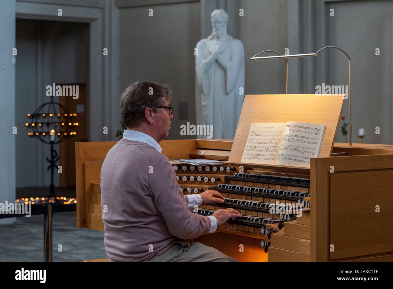L'Islanda, la regione della capitale, Reykjavik, Hallgrimskirkja, uomo giocando l'organo, organo a canne progettato dal tedesco organaro Johannes Klais Foto Stock
