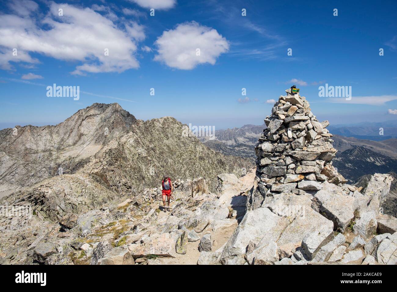 Francia, Hautes Pirenei, Parco Nazionale dei Pirenei, giovane escursionista alla sommità del picco del Turon de Néouvielle (3035m), il picco Neouvielle (3091m) e il picco dei tre consulenti (3039m) in background Foto Stock