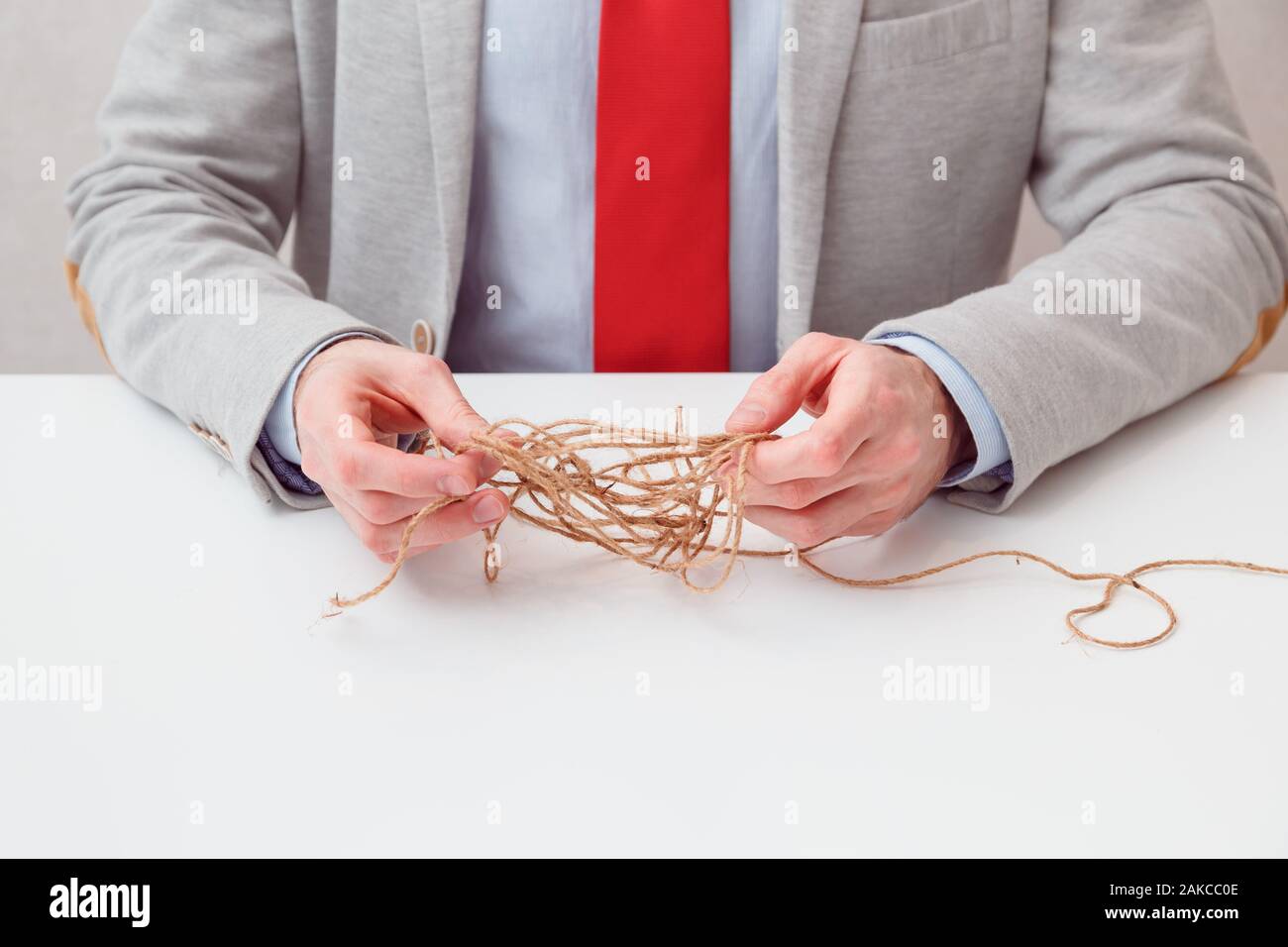 Imprenditore solo tentare di svolge il filo aggrovigliato sfera come puzzle fuori situazione. Foto concettuale. Foto Stock